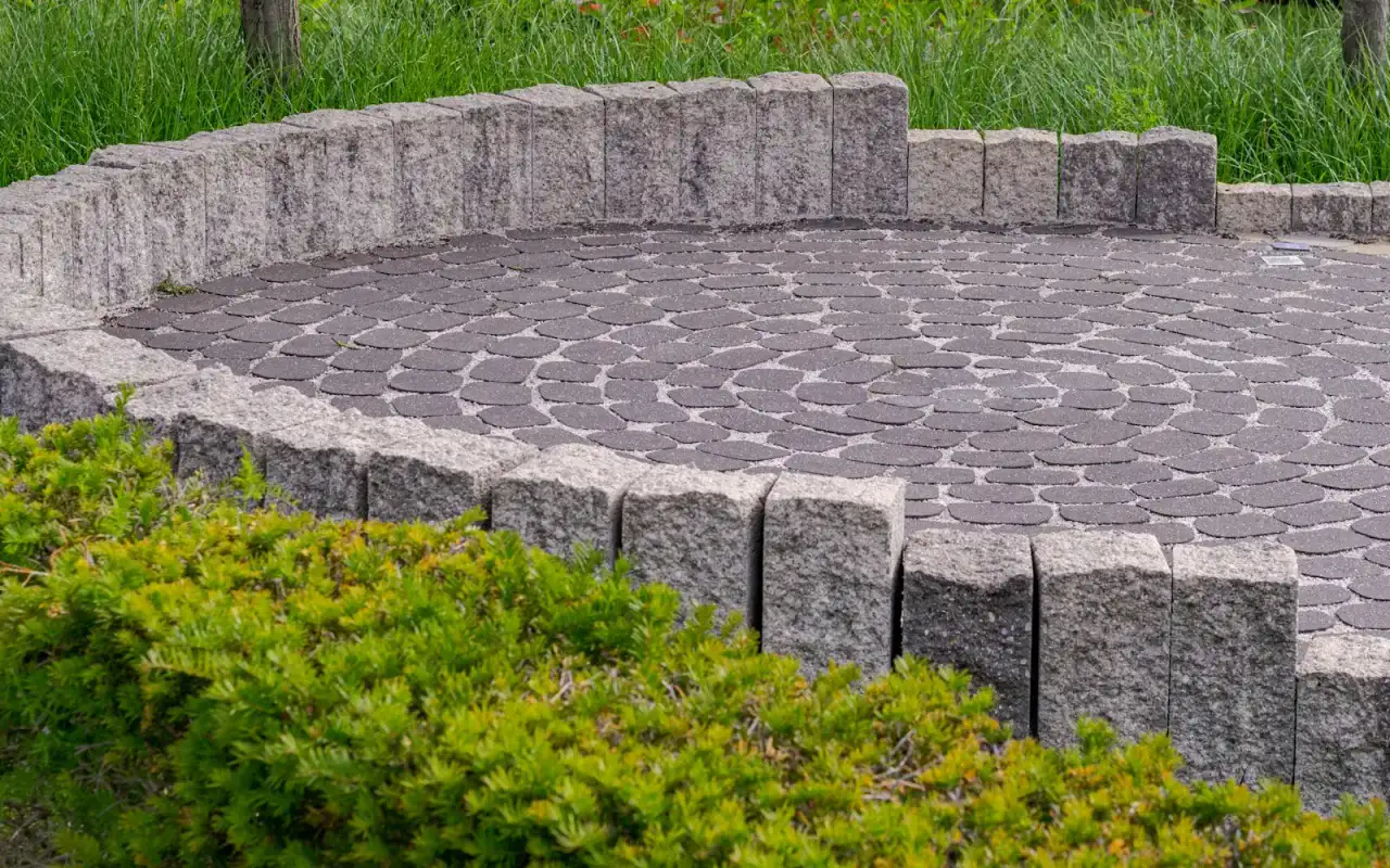 Circular stone-paved patio edged by a low granite wall